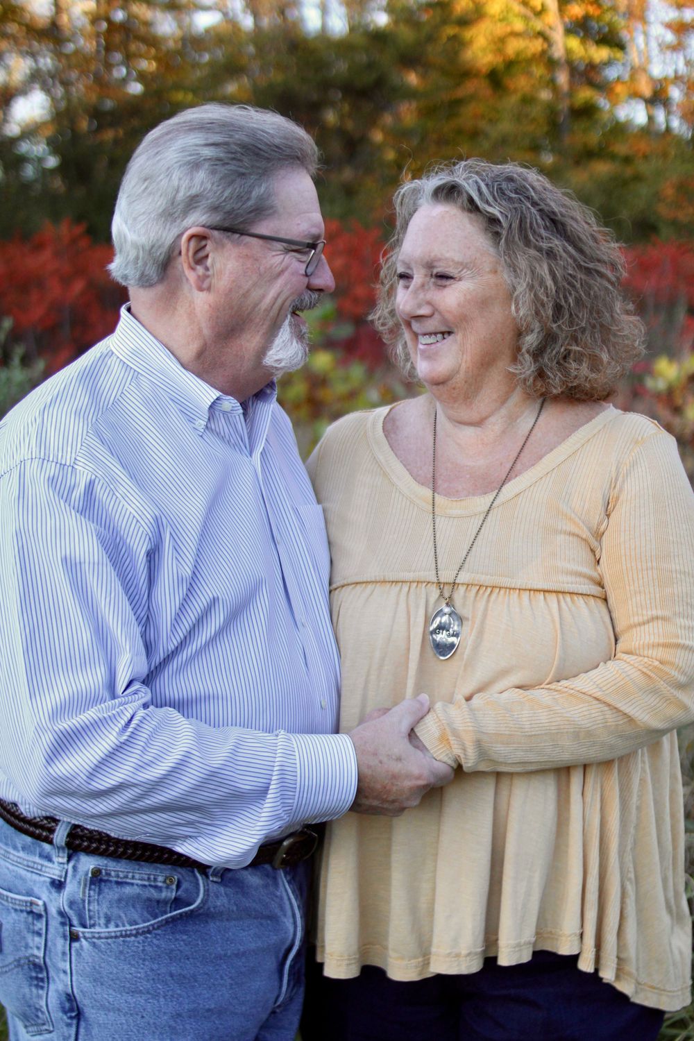 Mature couple in yellow and striped shirts sharing loving moments outdoors.