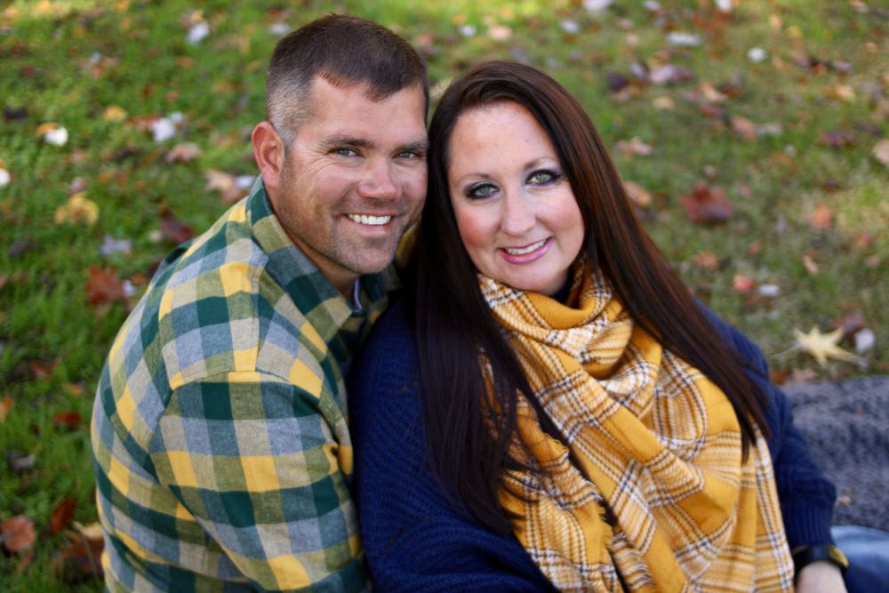 Couple in fall attire sharing intimate moments outdoors with yellow scarf and plaid shirt.