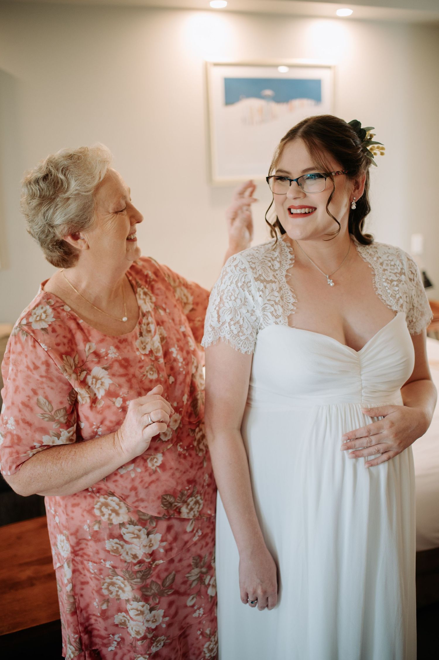 Two people sharing a joyful moment during wedding preparations in a brightly lit room.