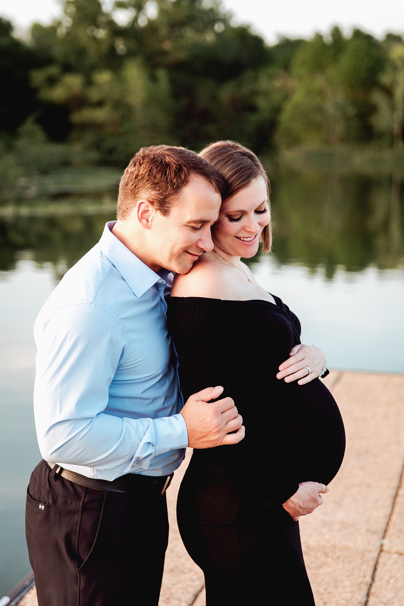 couple cuddled in close with the calm lake water in the background