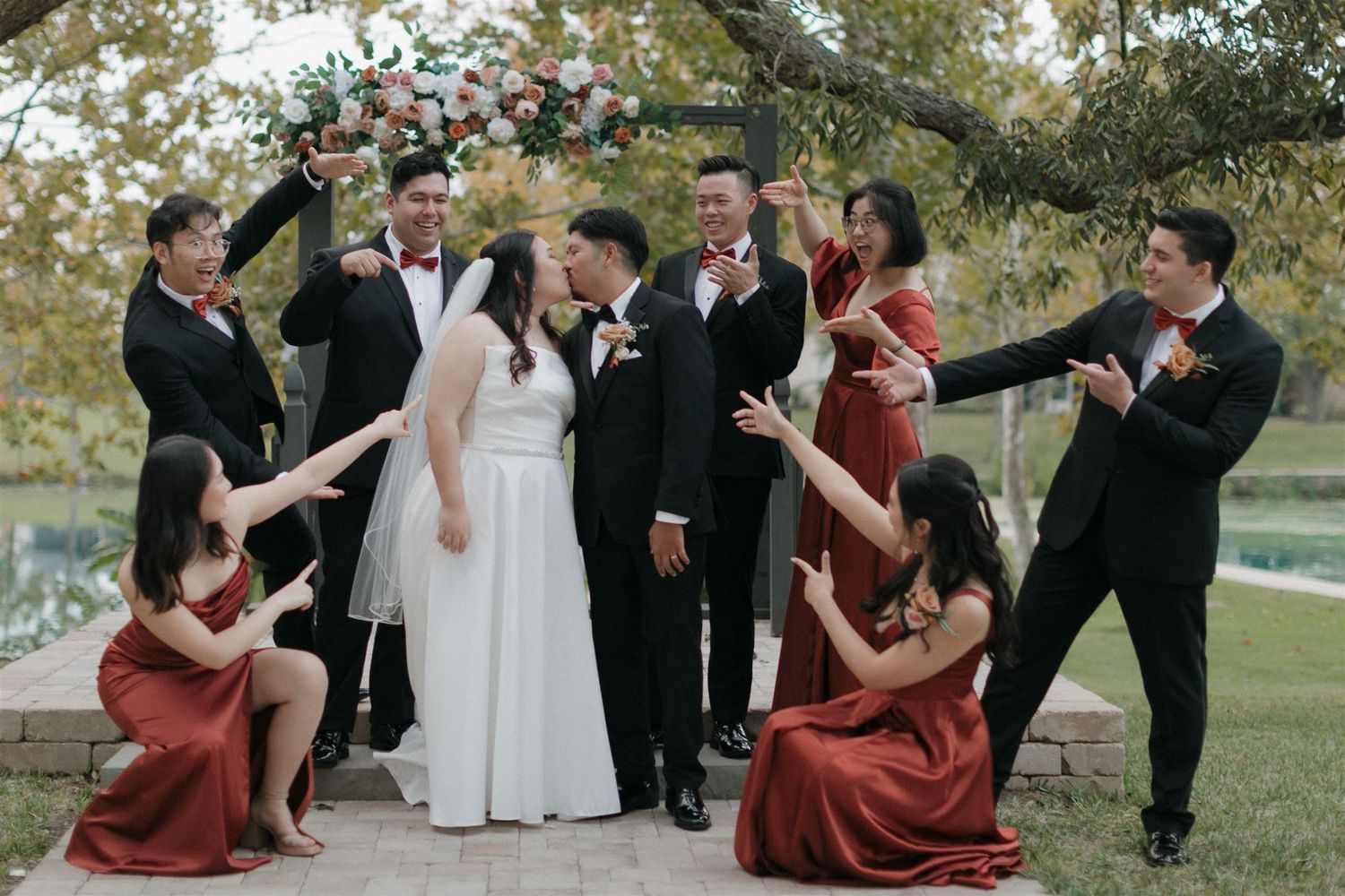 Wedding party strikes playful poses during outdoor photo session.