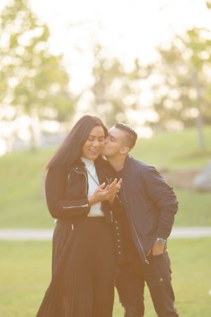 Joyful engagement moment captured in sunny park setting.