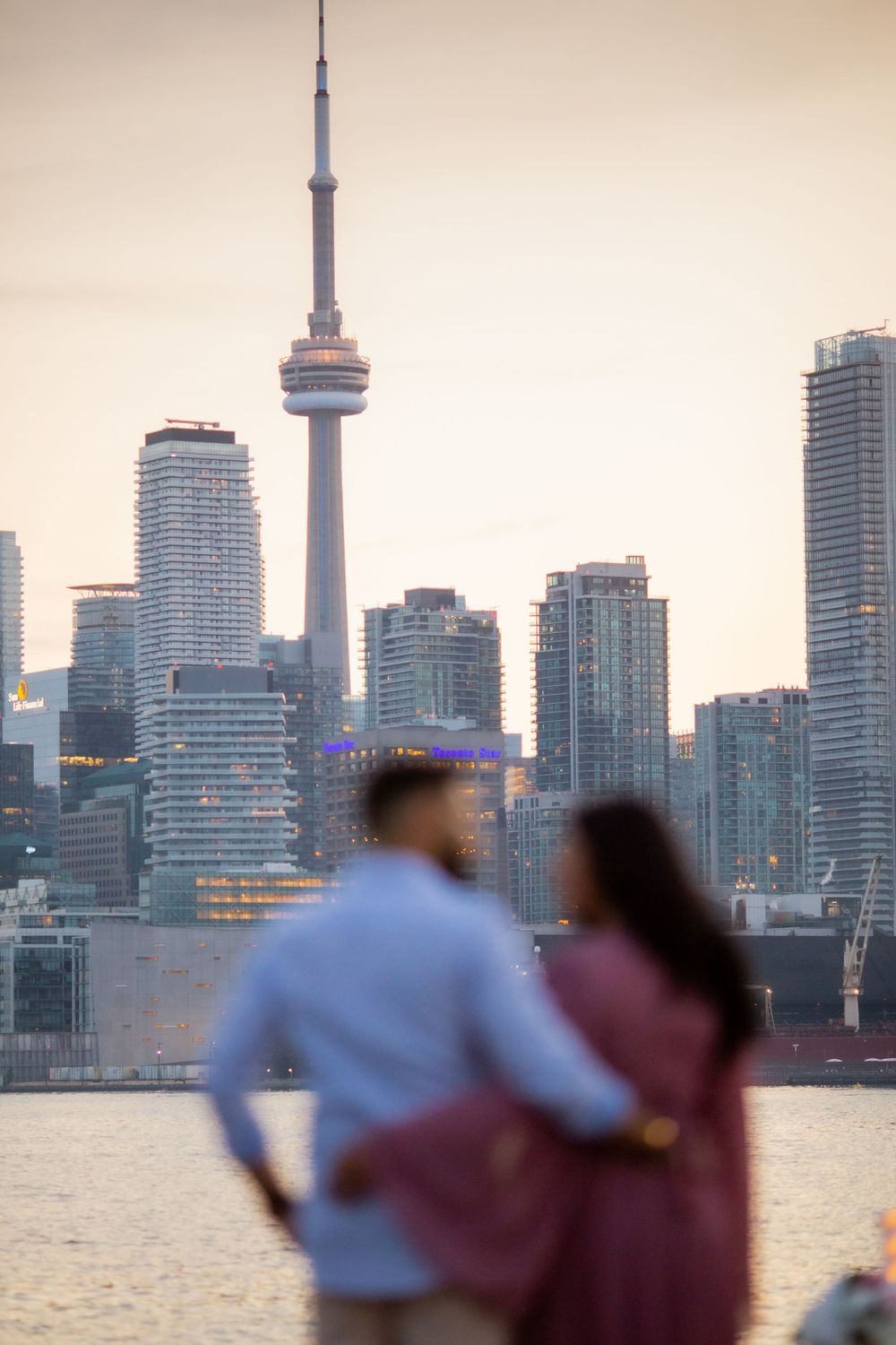 Silhouette of couple against Toronto skyline featuring CN Tower at sunset.