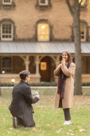 Autumn proposal scene outside historic brick building with falling leaves.