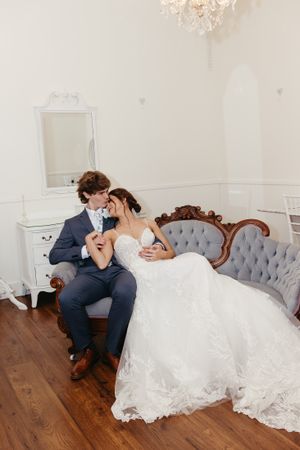 Romantic portrait of newlyweds sharing intimate moment on vintage sofa.