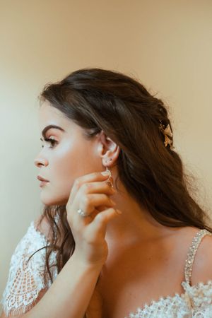 Side profile portrait showing elegant bridal jewelry and lace dress details.