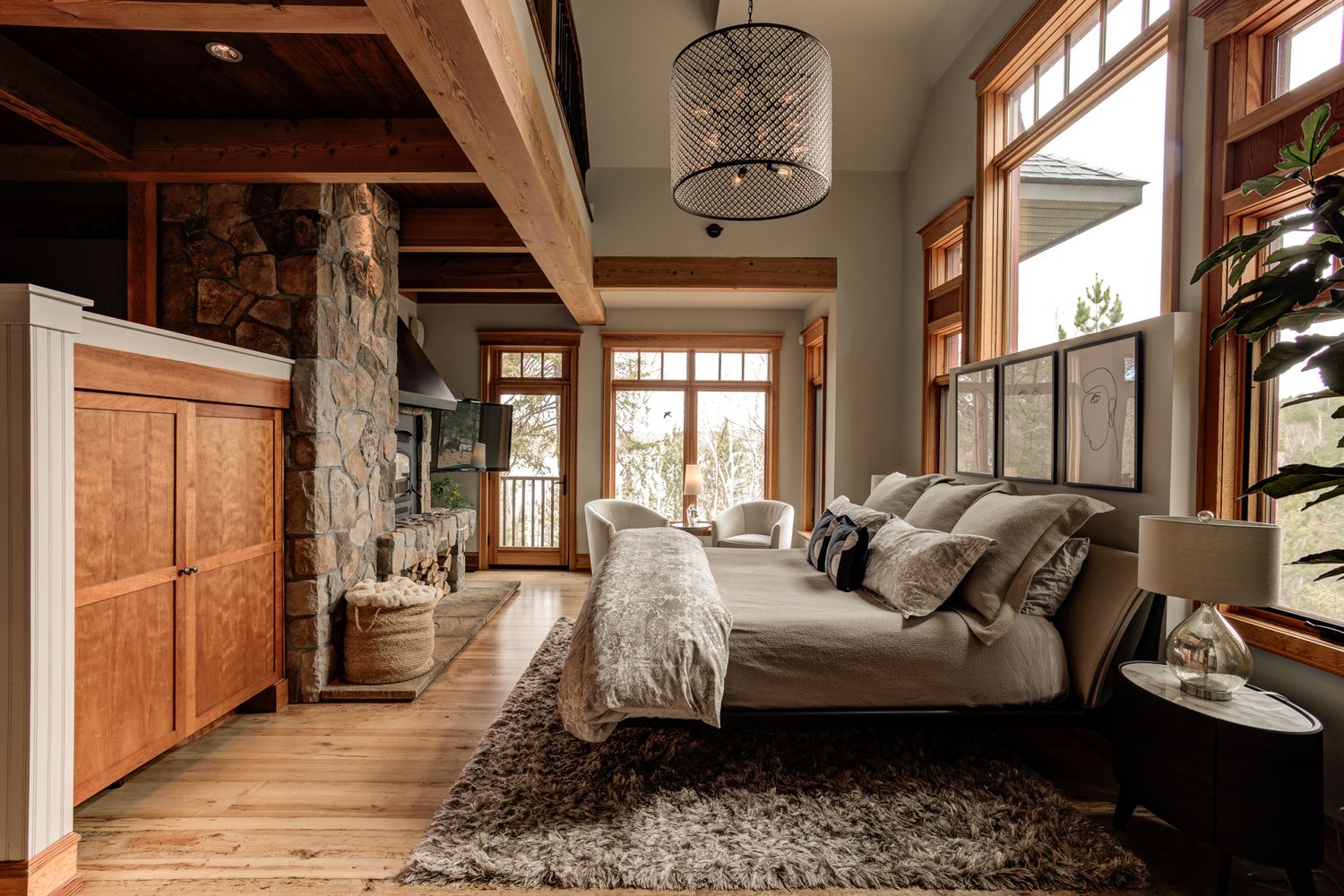Modern rustic bedroom with wooden beams, large windows and cozy neutral bedding.