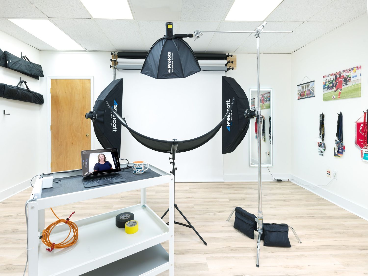 Photography studio setup with large lighting equipment, reflectors, and studio flash on light wood floors.