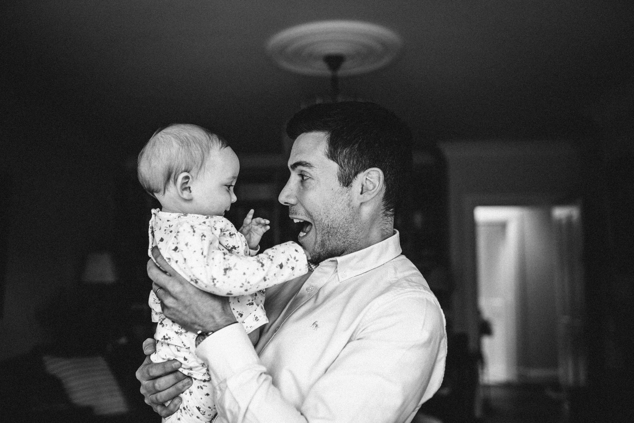 A tender black and white moment of parental bonding with a small baby in a patterned outfit.