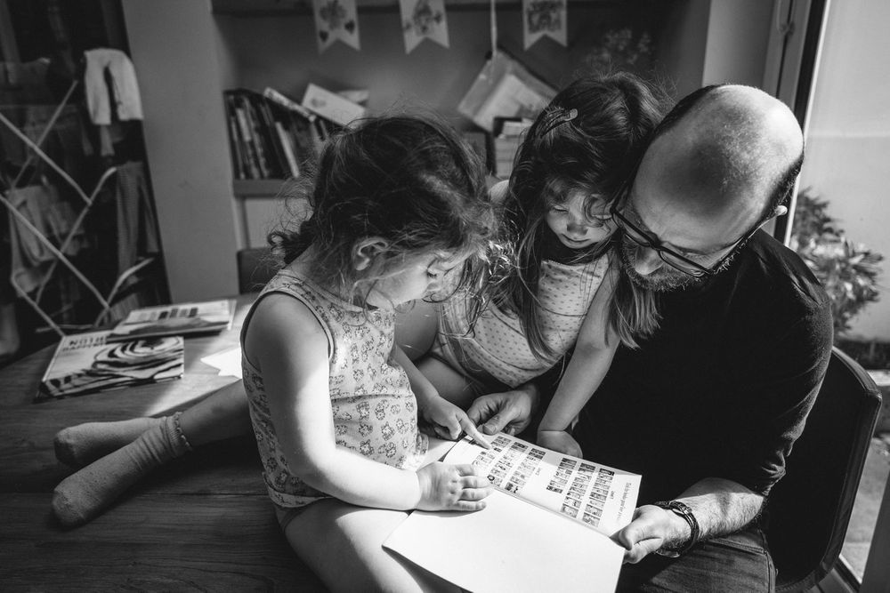 A family reading together while sitting on the floor of a room with bookshelves.