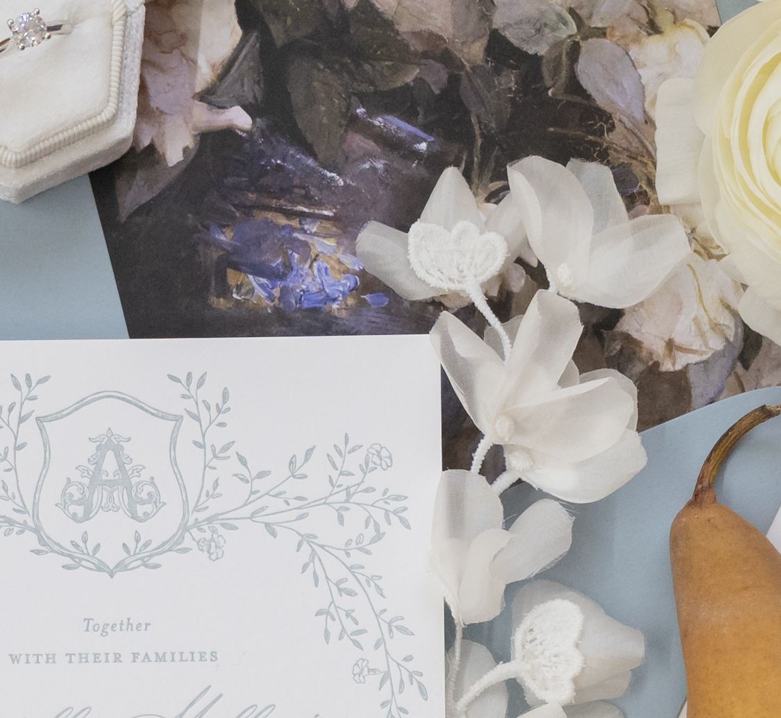 Close-up of wedding invitation monogram design with white floral details.