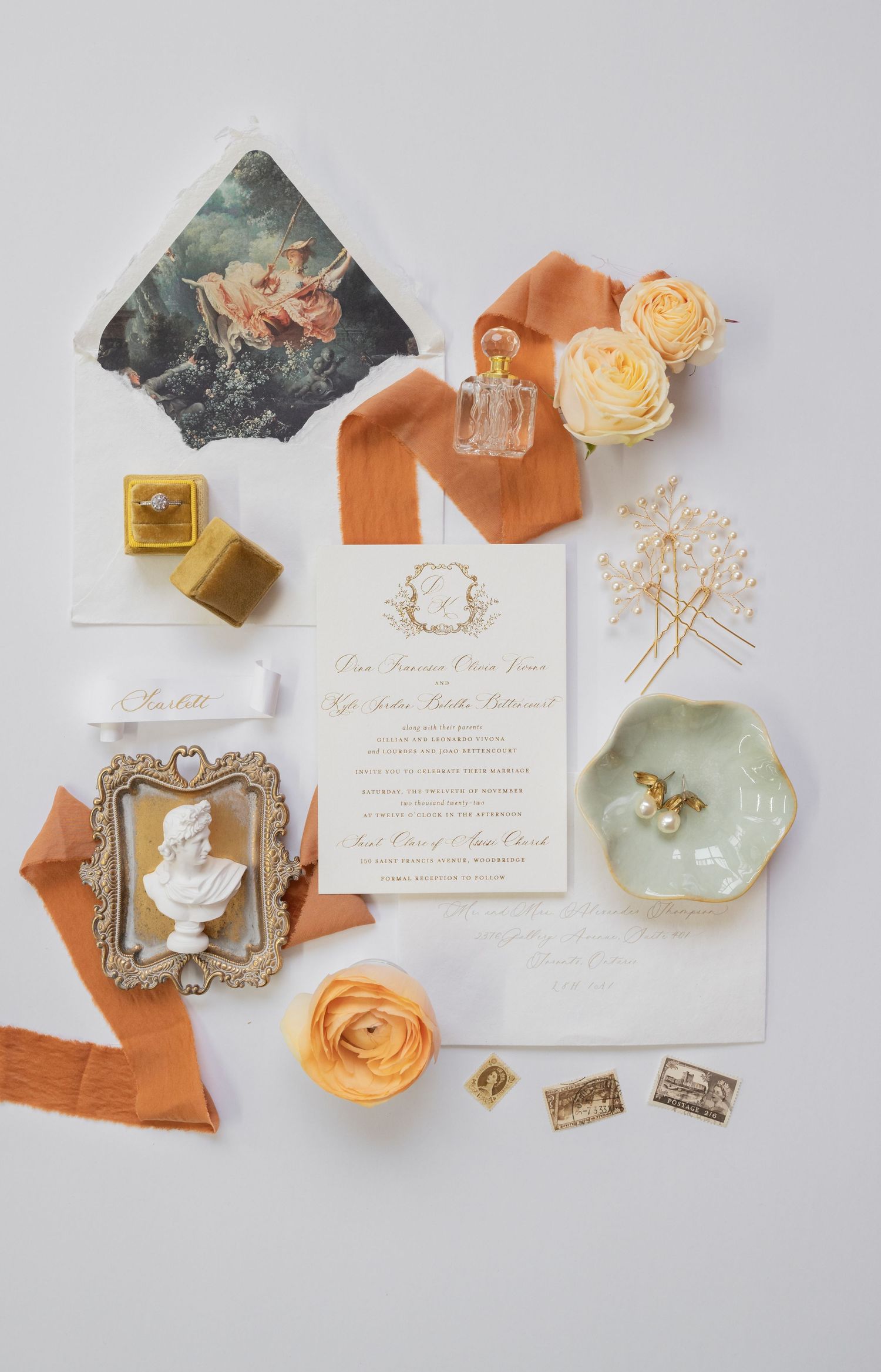 Wedding invitation flatlay with peach roses, vintage frames, and decorative accessories on white background.