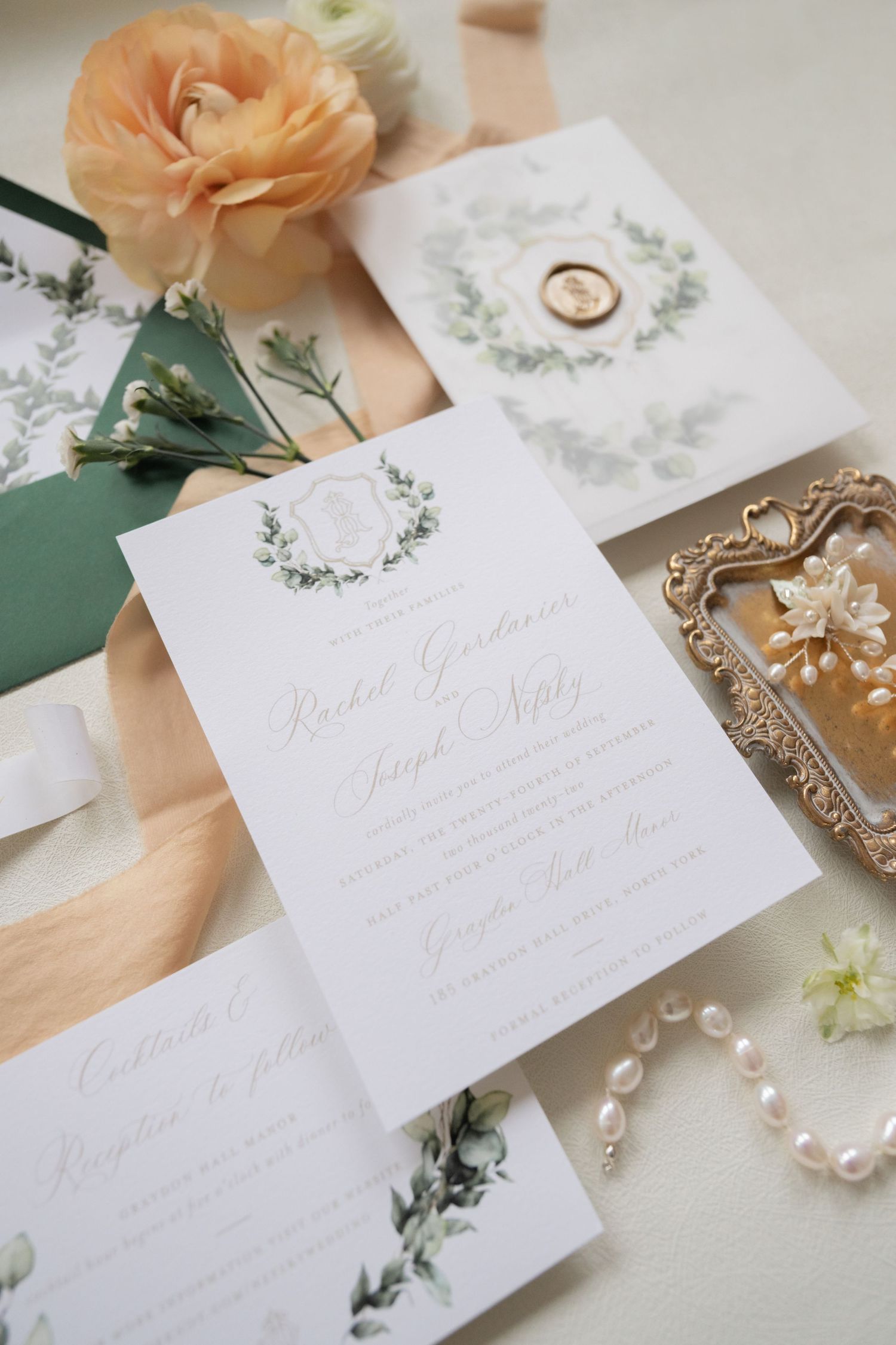 White wedding invitation with delicate greenery design and peach floral accents.