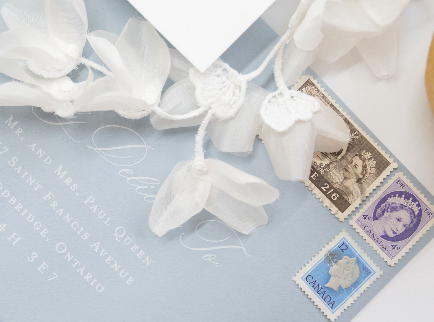 Wedding invitation with vintage postage stamps and white silk ribbon details.