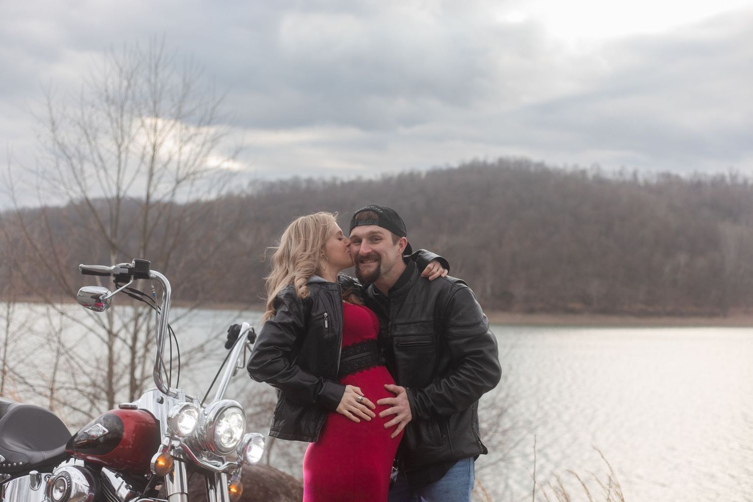 A couple shares a romantic winter moment on a snowy lakeside with mountains in the background.