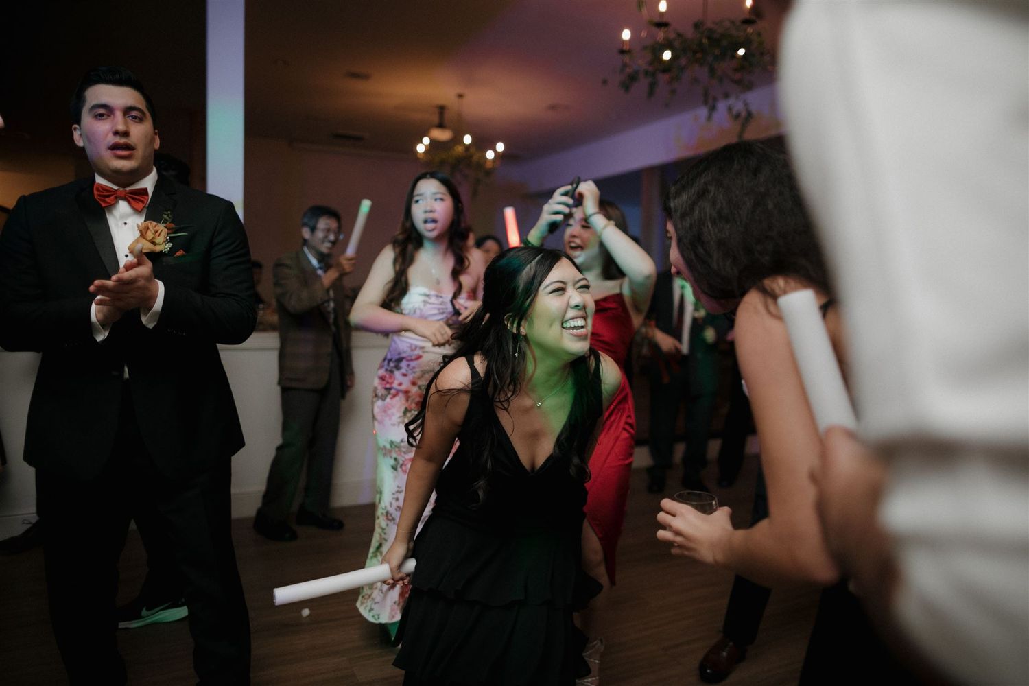 Wedding guests dance and celebrate during a lively reception party indoors.