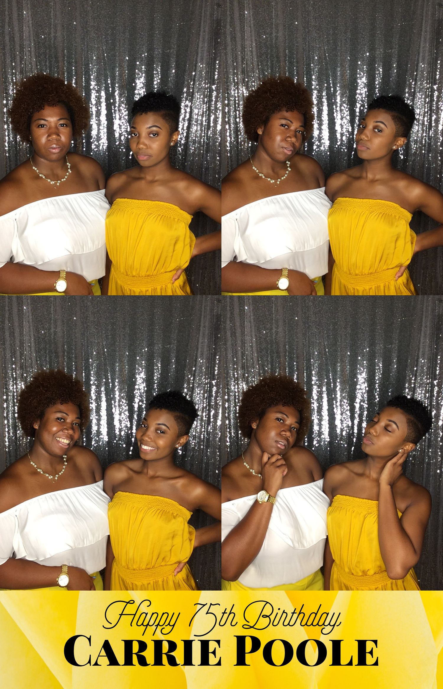 Two women in strapless dresses pose playfully in a photo booth with a silver backdrop.