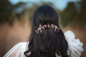 Close-up back view of dark hair with an elegant rose gold crystal and pearl bridal hair vine.