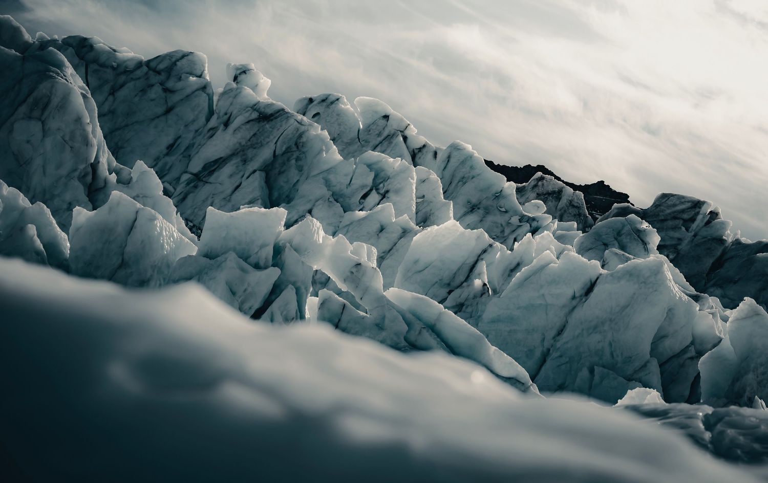 Dramatic blue ice formations of a glacier under cloudy skies.