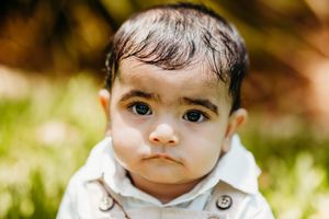 Artistic close-up portrait with natural lighting and greenery background.
