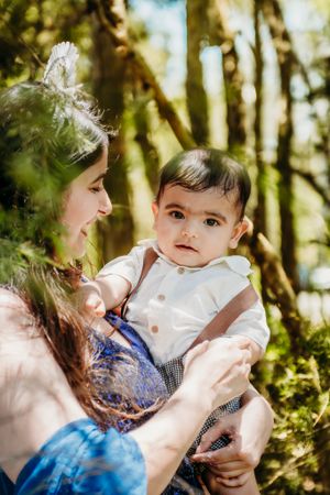 Tender outdoor family moment captured in sunlit forest setting.