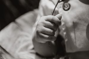 Close-up black and white photo showing gentle hands holding a baby.