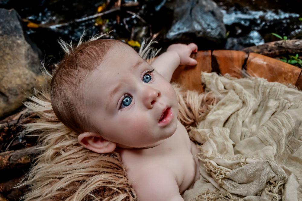 Baby lying on cream colored fabric with natural lighting and soft shadows.