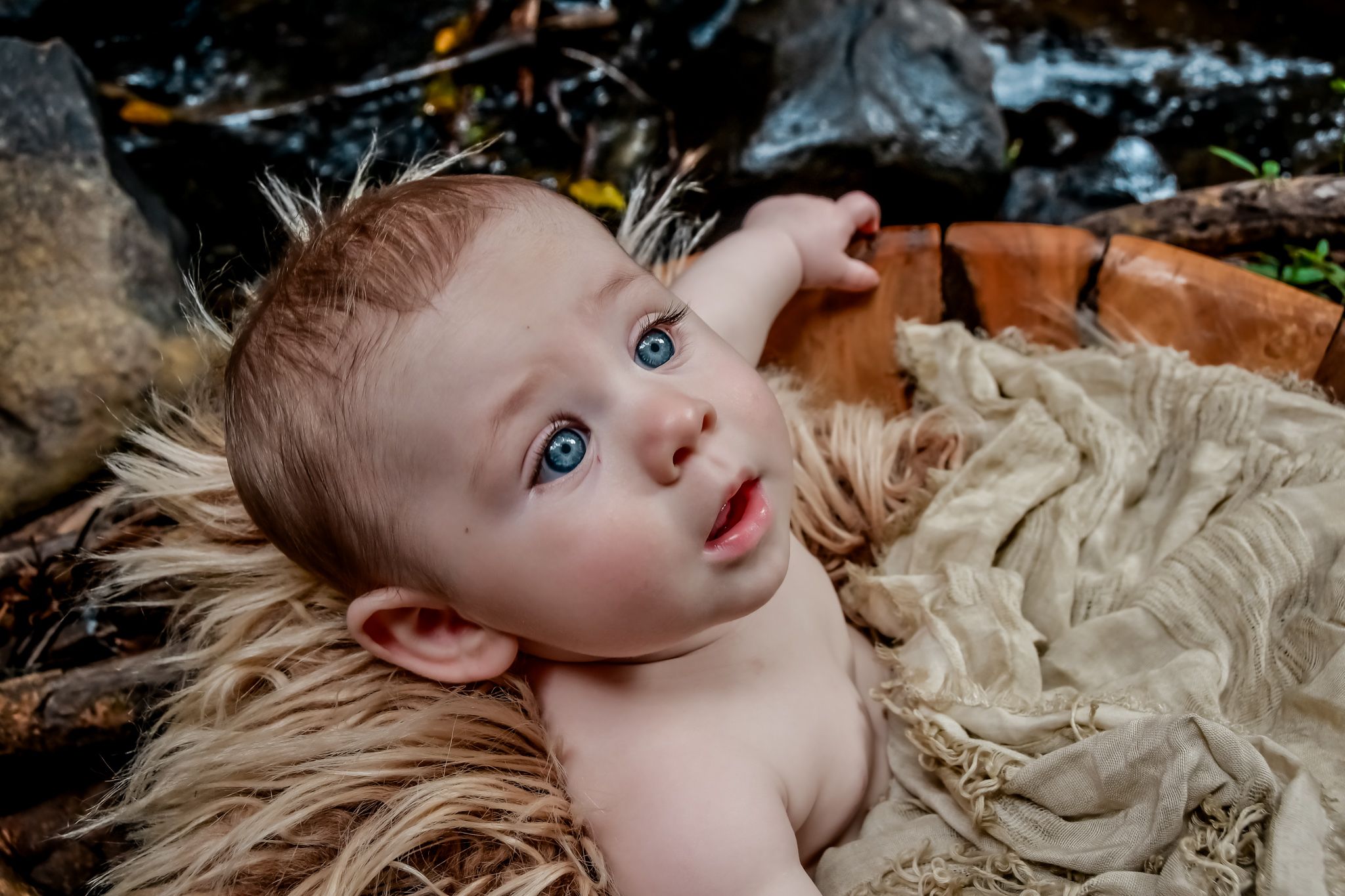 Baby lying on cream colored fabric with natural lighting and soft shadows.