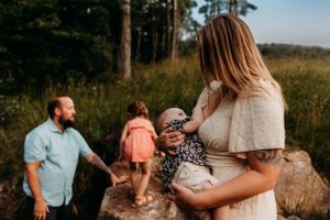 A family spending time together on rocky terrain surrounded by tall pine trees.