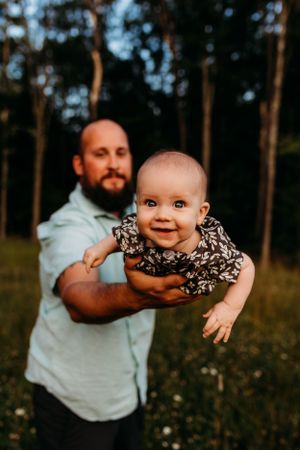 A heartwarming outdoor family portrait in a wooded meadow during golden hour.