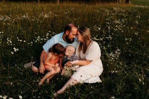 Intimate family moment captured in flowering meadow during golden hour.