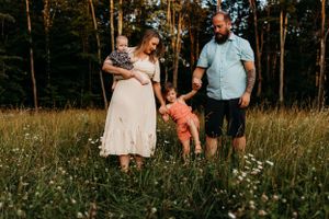 Family playing and laughing together in a summer field with wildflowers.
