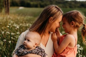 Tender family moment shared in blooming wildflower field at sunset.