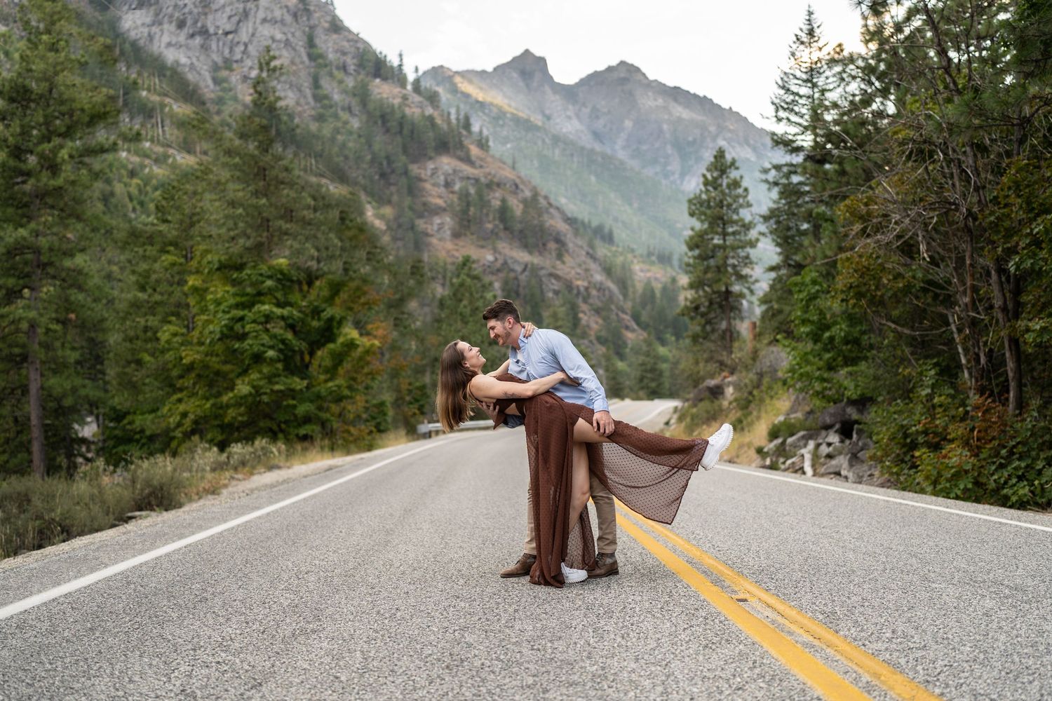 A romantic dip pose on a mountain road with dramatic peaks in the background.