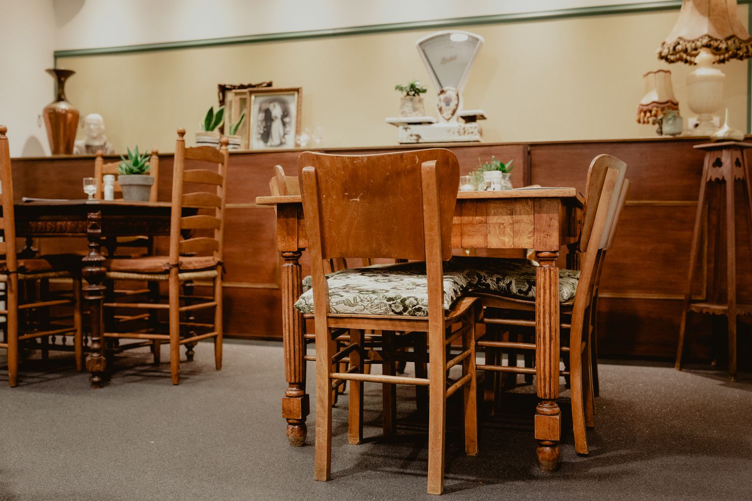 Rustic restaurant interior with wooden chairs and tables in warm lighting.