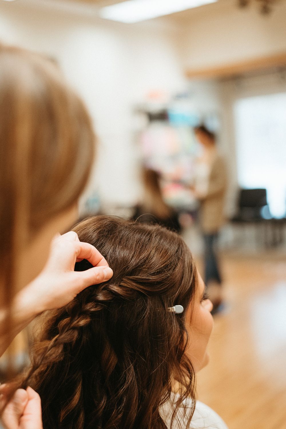 Hairstylist creating an intricate braid hairstyle in a salon setting.