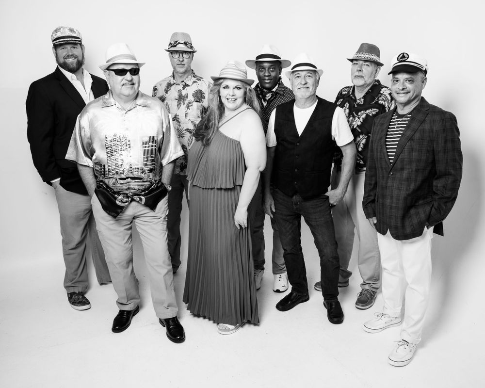Black and white group photo showing people lined up in casual attire against a white backdrop.