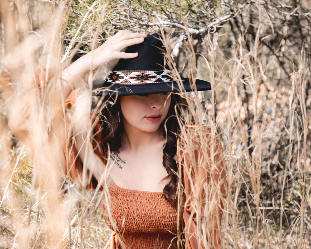 Artistic outdoor portrait series in a field of tall dried grass and natural lighting.