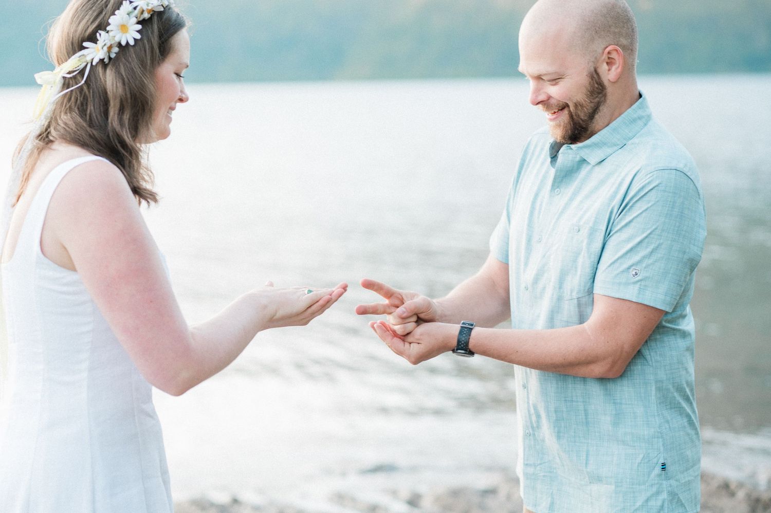 couple plays rock, paper, scissors before exchanging vows in front of lake.