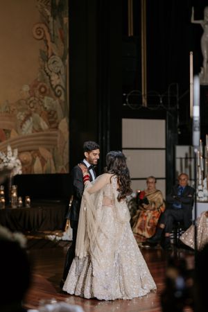 Couple dancing at wedding reception in formal attire with decorated backdrop.