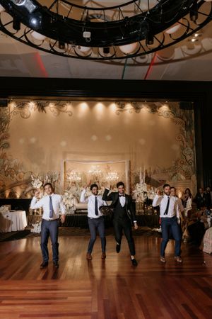 Dance performance at a formal wedding reception features coordinated moves on a polished wooden floor.