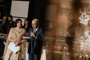 Formal event speakers on stage with elegant lighting and floral decorations.