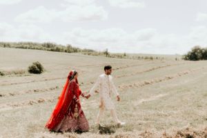 Minimalist wedding portrait of couple in traditional attire walking through rolling hills.