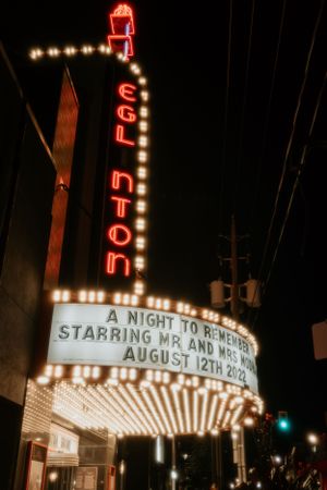 Vintage neon Avalon theater marquee lit up at night displaying a wedding celebration date.