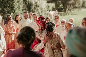 Joyous outdoor wedding celebration with guests in traditional Indian and western attire.