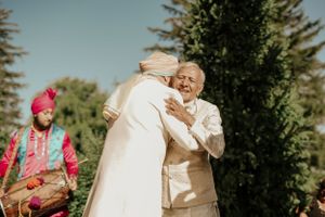 Two people hugging during an outdoor wedding ceremony with traditional attire.