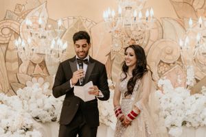 Wedding ceremony with elegant floral backdrop, crystal chandeliers and formal attire.