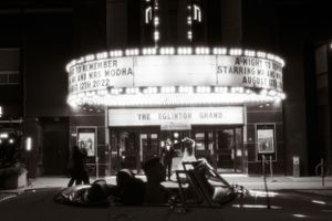 Vintage black and white photo of The Eglinton Grand theater marquee entrance at night.