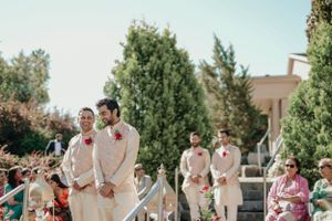 Wedding party in cream-colored attire standing on stone steps during an outdoor ceremony.