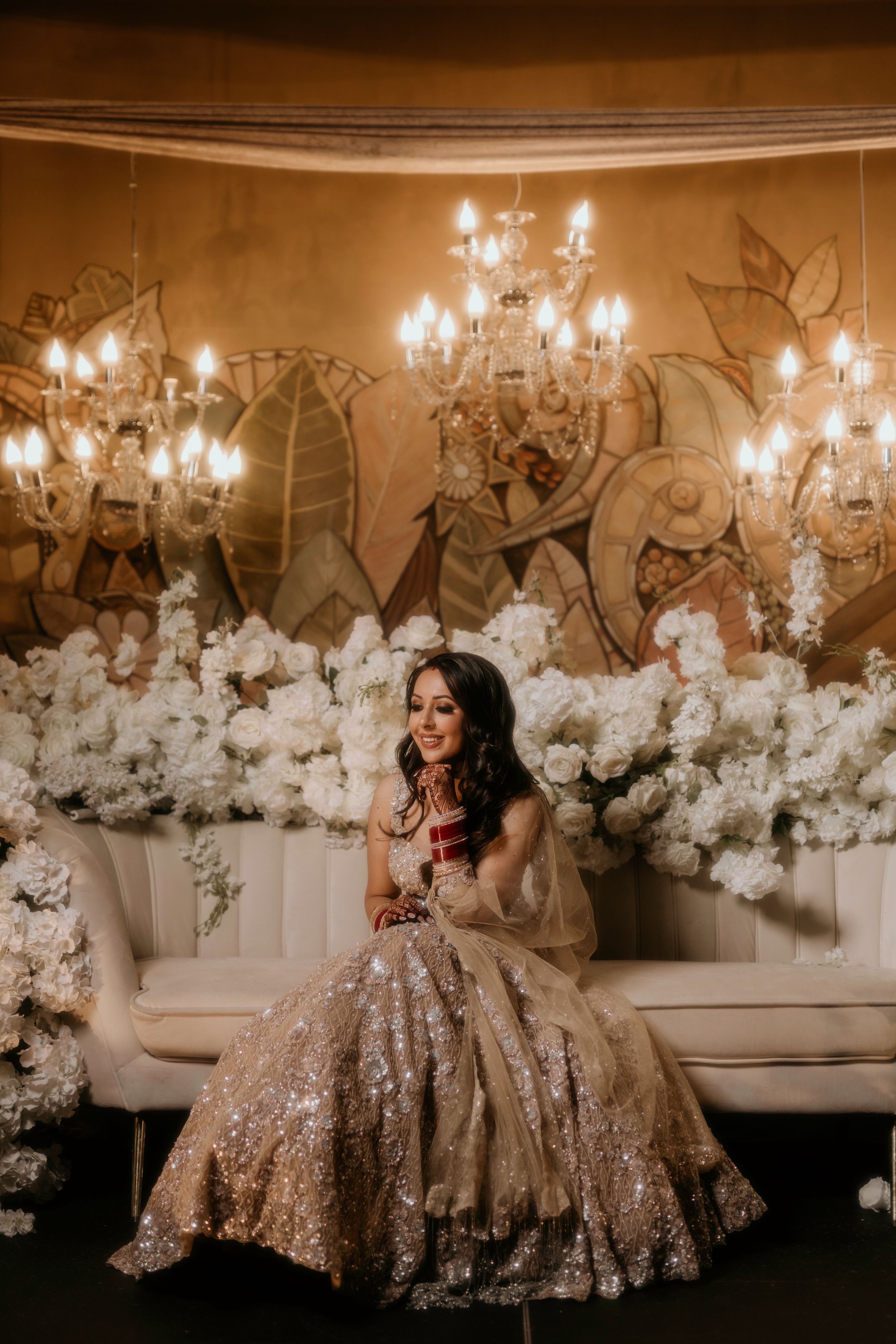Elegant wedding setting with crystal chandeliers and white floral arrangements creates romantic ambiance.